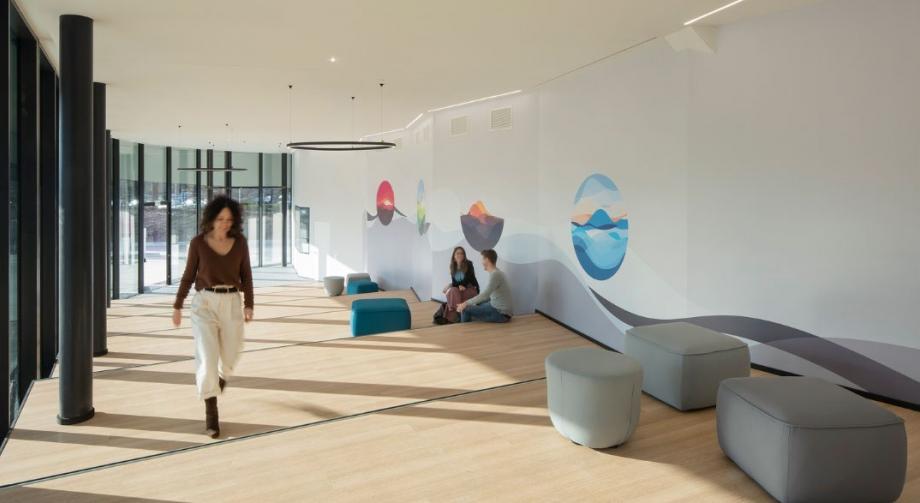 Esempio di una soluzione di postazione di lavoro ibrida di Studio Alliance caratterizzata da uno spazio di breakout minimalista con sgabelli per sedersi