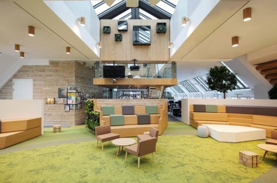 Voorbeeld van een hybride werkplekoplossing van Studio Alliance met een breakout-ruimte met een groen tapijt en hoge plafonds